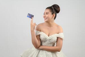 Young asian beautiful bride posting with credit card in hand photo