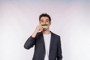 Portrait of Young smiling handsome businessman showing credit card isolated over white background photo