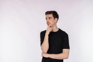 Portrait of young man thinking touching chin isolated over white background photo