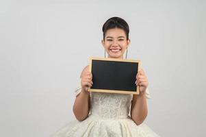 Young asian beautiful bride pose with blank blackboard in hand photo