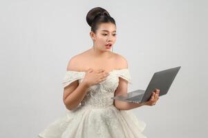 Young asian beautiful bride pose with laptop computer in hand photo