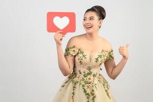 Asian beautiful bride smiling and posing with heart sign on white background photo