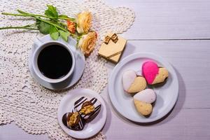 romantic flowers with coffee and sweet treats on the table photo