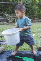 Little child holding pot to prepare plants for planting. Toddler boy standing to prepare to plant to Mother's little helper. Gardening. Hobbies at home horticulture. Leisure activities family concept photo