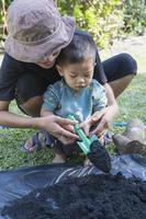 Toddler son and mother teaching little son preparing the soil to plant in a garden, mother and son relationship. Mommy's little helper. Gardening. Leisure activities family concept photo