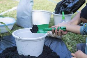 primer plano del hijo pequeño y la mano de la madre enseñando al hijo pequeño a preparar el suelo para plantar en el jardín, la relación madre e hijo. la pequeña ayudante de mamá. jardinería. concepto de actividades de ocio foto