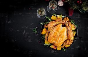 Baked turkey or chicken. The Christmas table is served with a turkey, decorated with bright tinsel. Fried chicken. Table setting. Christmas dinner. Top view photo