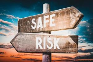 Safe, Risk - Wooden Signpost with Two Arrows, Sunset Sky in Background photo