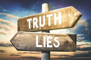 Truth, Lies - Wooden Signpost with Two Arrows, Sunset Sky in Background photo