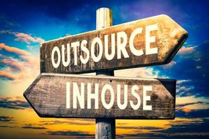 Outsource, Inhouse - Wooden Signpost with Two Arrows, Sunset Sky in Background photo