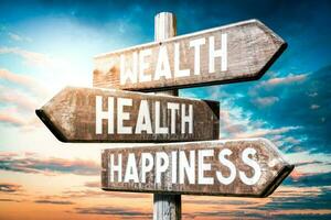 Wealth, Health, Happiness - Wooden Signpost with Three Arrows, Sunset Sky in Background photo