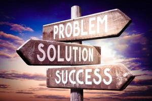 Problem, Solution, Success - Wooden Signpost with Three Arrows, Sunset Sky in Background photo