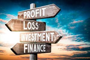 Profit, Loss, investment, Finance - Wooden Signpost with Four Arrows, Sunset Sky in Background photo