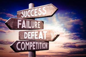 Success, Failure, Defeat, Competition - Wooden Signpost with Four Arrows, Sunset Sky in Background photo