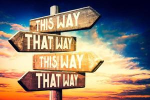 This Way - Wooden Signpost with Four Arrows, Sunset Sky in Background photo