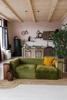 Stylish Scandinavian interior of the living room with designer green velour sofa, wooden furniture, plants, carpet, dining table photo