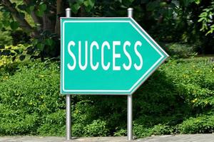 Success - Green Arrow Signpost and Bush in Background photo