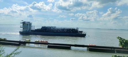 A boat tie in the river beach with a green tree blue sky electric tower  in the background photo