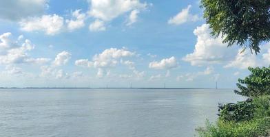 A boat tie in the river beach with a green tree blue sky electric tower  in the background photo