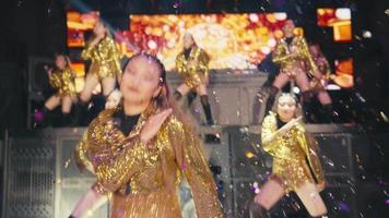A group of Asian dancers with golden costumes dancing with enthusiasm and shiny clothes