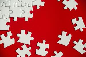 Top view of missing jigsaw puzzle on red cover background. Copy space photo