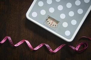 Top view weight scape with wooden floor and measuring tape background. Weight loss concept. photo