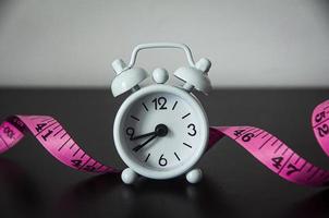 White alarm clock with measuring tape background. photo