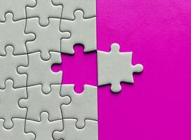 Top view of missing jigsaw puzzle with customizable space for text on pink color background. Copy space concept. photo