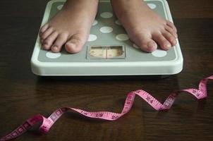 Straight view of measuring tape and feet on weight scale . Weight loss concept. photo