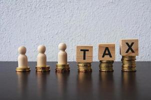 Coins Stack with wooden doll model and TAX Text on wooden blocks - Tax return concept photo