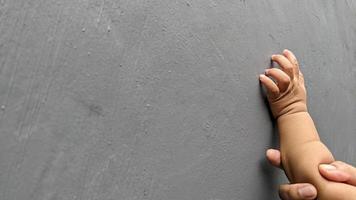 mother and baby's hands touch against a gray wall background photo