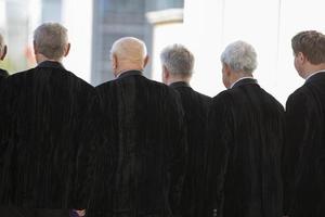 May 09, 2022. Belarus, the village of Lyaskovichi. Festival of ethnic cultures.A group of old men in black jackets stand with their backs. Retirees look ahead. photo