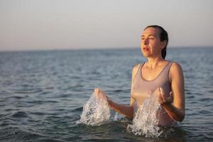 un de edad mediana mujer se baña en el mar y salpicaduras agua. foto