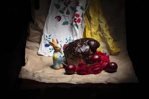 Beautiful Easter background. Chocolate cake with colored eggs and an Easter bunny on the background of an embroidered shirt. photo