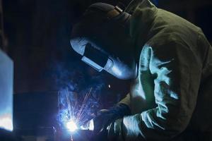 un trabajador en un soldadura traje soldadura trabajo con volador chispas. foto