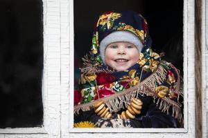 un pequeño niña en un ruso Pañuelo con Bagels a el maslenitsa día festivo. foto
