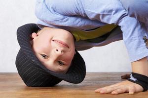 A boy in a hat grimaces with his head down. A funny child in a classic wide-brimmed hat. photo