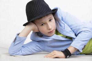 A handsome boy in a jacket and black hat looks at the camera. photo