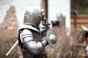 Antique medieval knight in armor with a protective metal shield. Iron age. photo