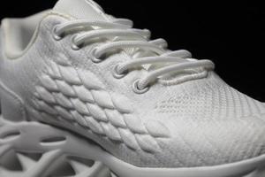 White fabric sneaker with embossed sole on a black background close-up. photo