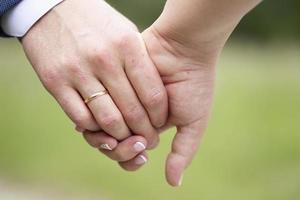 un del hombre mano con un Boda anillo sostiene un mujer mano. foto