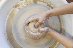 Close-up of a potter's hands with an item on a potter's wheel. Working with clay. Clay workshop. Craft training. photo