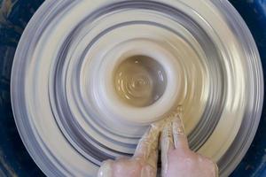 Close-up of a potter's hands with an item on a potter's wheel. Working with clay. Clay workshop. Craft training. photo