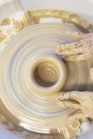 Close-up of a potter's hands with an item on a potter's wheel. Working with clay. Clay workshop. Craft training. photo