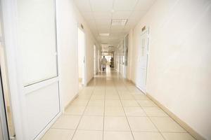 Long hospital corridor with a silhouette of a doctor in a protective suit. photo