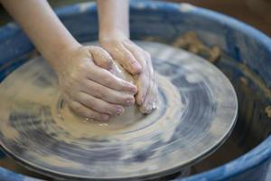 Close-up of a potter's hands with an item on a potter's wheel. Working with clay. Clay workshop. Craft training. photo