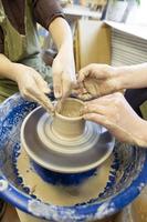 Close-up of a potter's hands and a child's hand with an item on a potter's wheel. Working with clay. Clay workshop. Craft training. photo