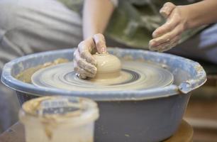 Close-up of a potter's hands with an item on a potter's wheel. Working with clay. Clay workshop. Craft training. photo