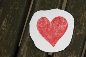 rojo corazón hecho de papel en un de madera antecedentes. foto