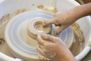 Close-up of a potter's hands with an item on a potter's wheel. Working with clay. Clay workshop. Craft training. photo